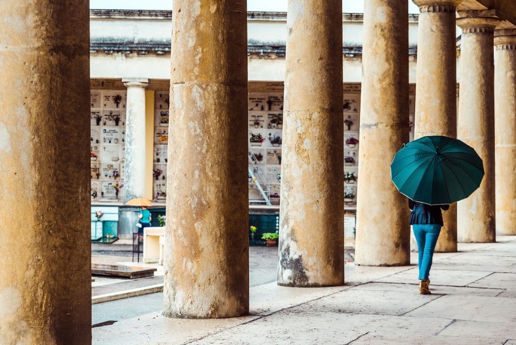 young woman with an umbrella walking next to an ancient building