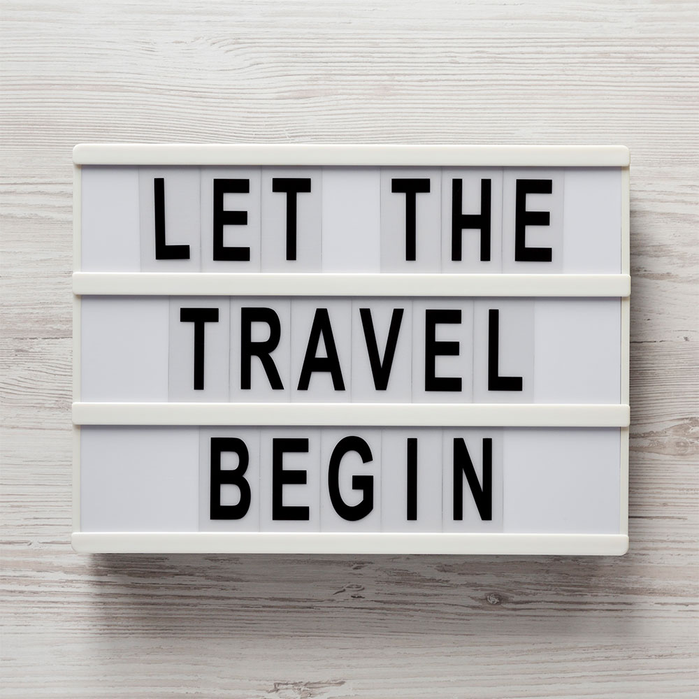 let the travel begin on a lightbox on a white table