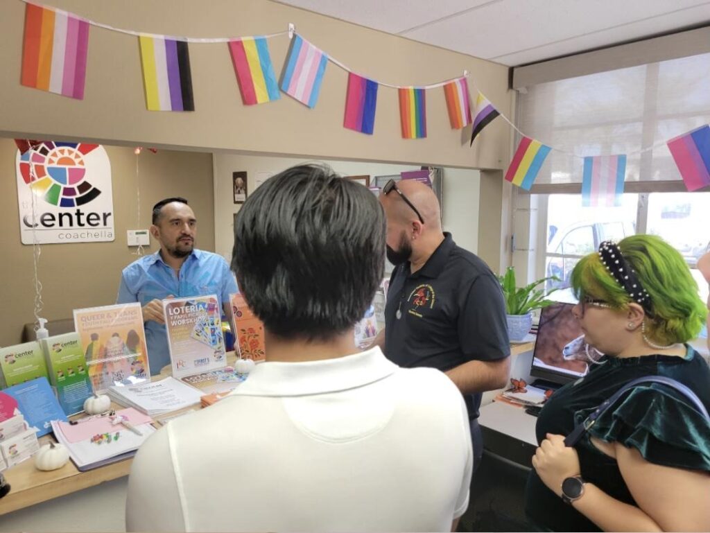 Visitors talk with staff at the front desk of The Center Coachella, an LGBTQ+ community center decorated with pride flags, in October 2025.