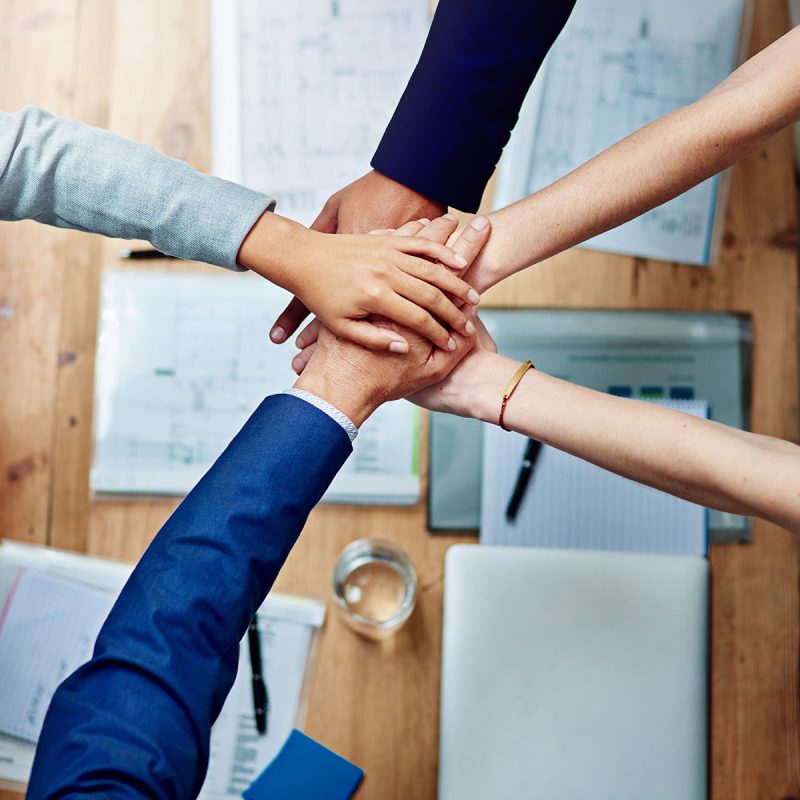 five people with hands in a huddle